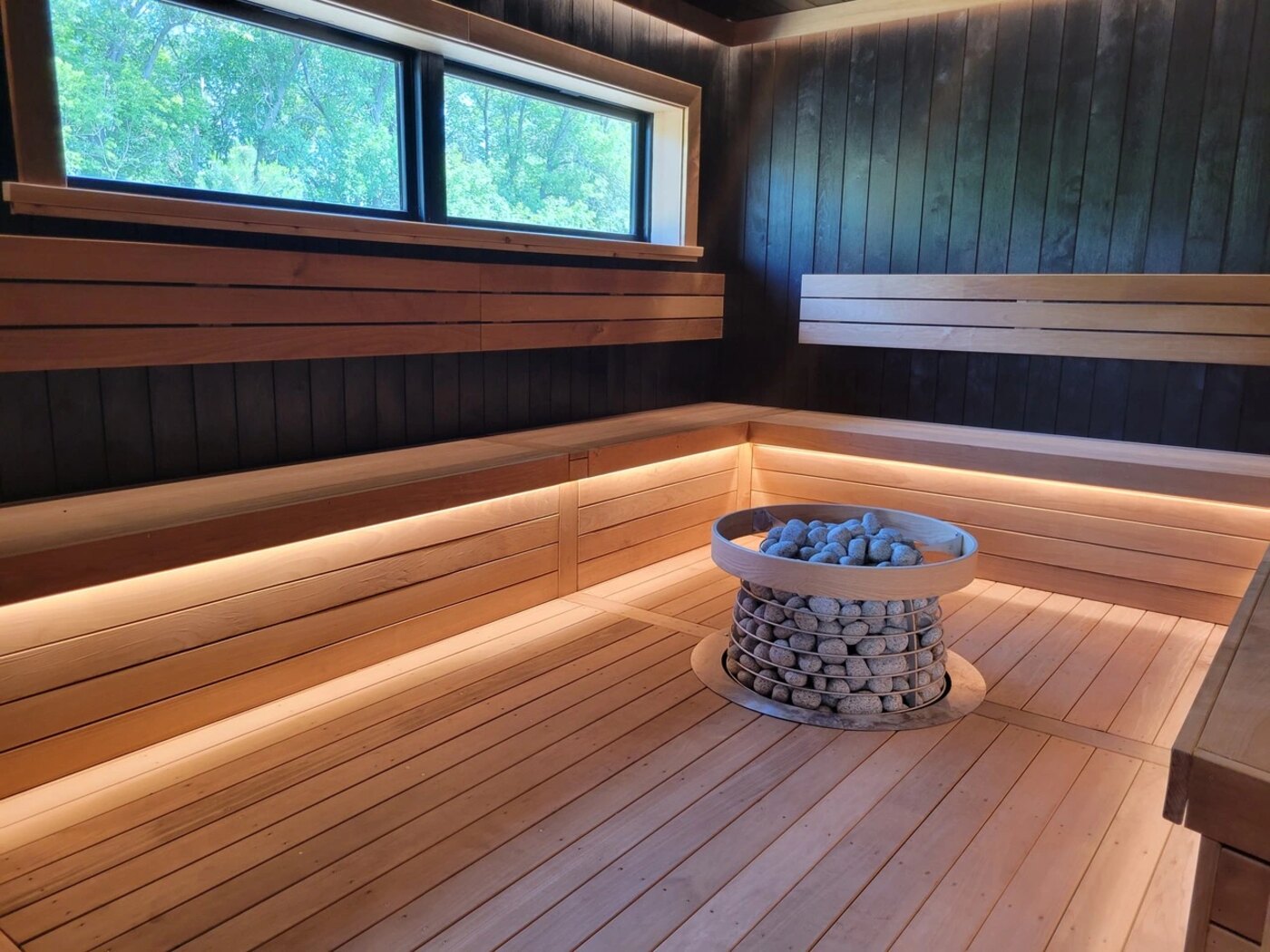 Traditional Finnish sauna with cedar benches and a stone-basket heater