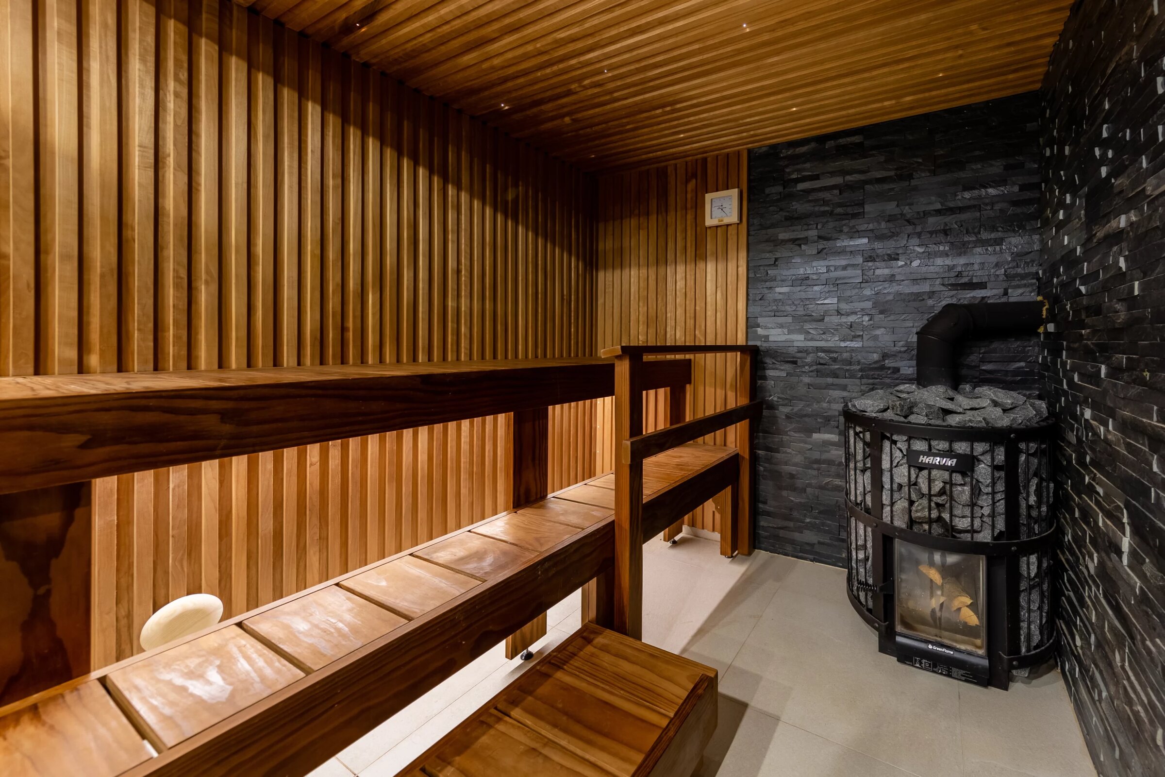 Warmly lit custom sauna interior with dark stone accent wall and cedar paneling