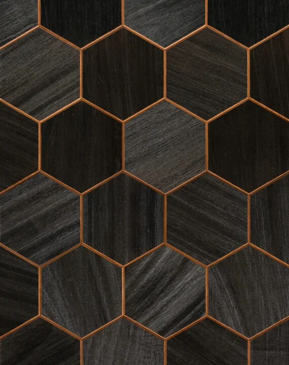 Close-up of dark thermally treated Abachi hexagon wood paneling with bronze grout lines